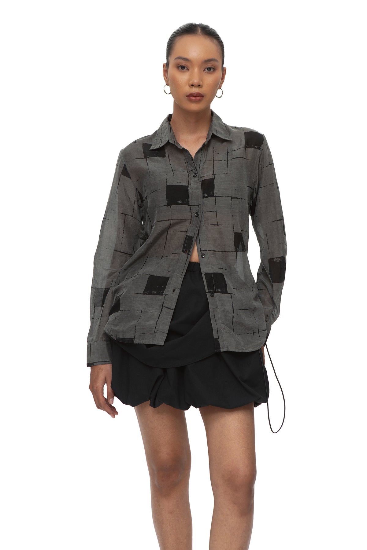 Model wearing bio-washed cotton silk shirt with abstract black grid print, worn open over a black bubble skirt