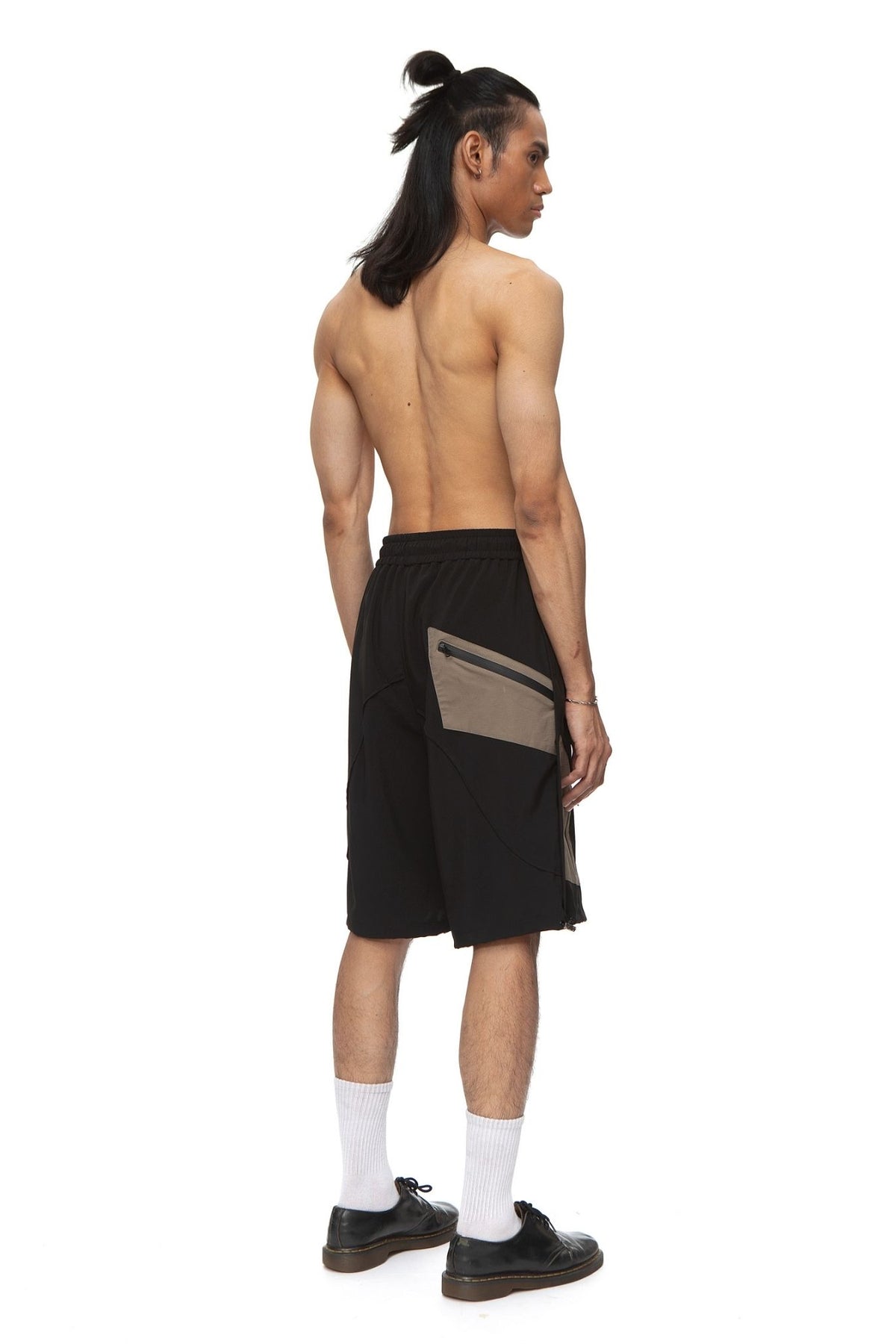 Model wearing black and taupe colorblock technical shorts with drawstring waist.