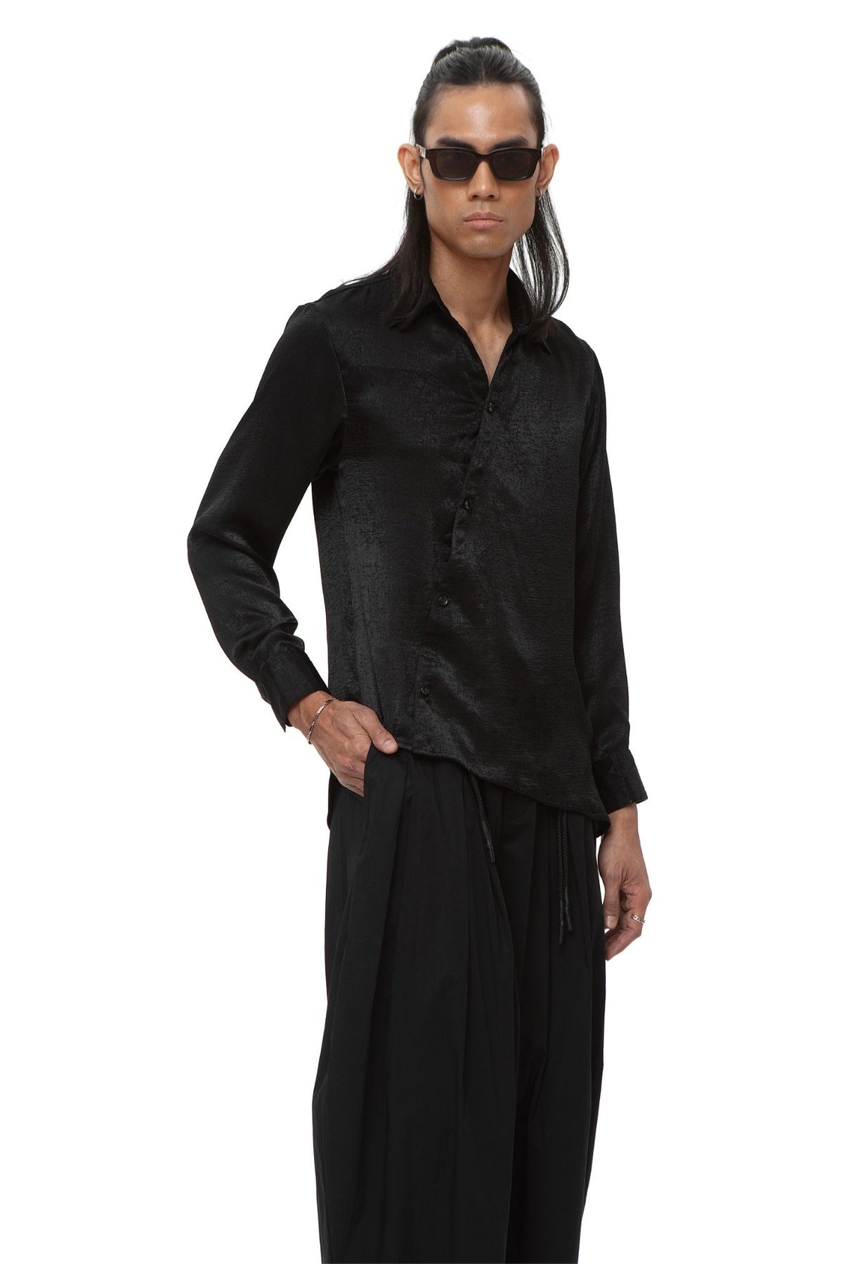 Model wearing black satin popover shirt with point collar and asymmetrical button placket.
